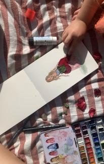 A childs hand sticking flower petals in form of a dress